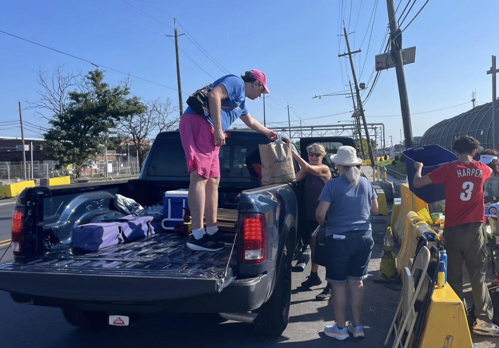 We are looking into the bed of a blue pickup truck as people unload supplies for the families with relatives in Delaney Hall